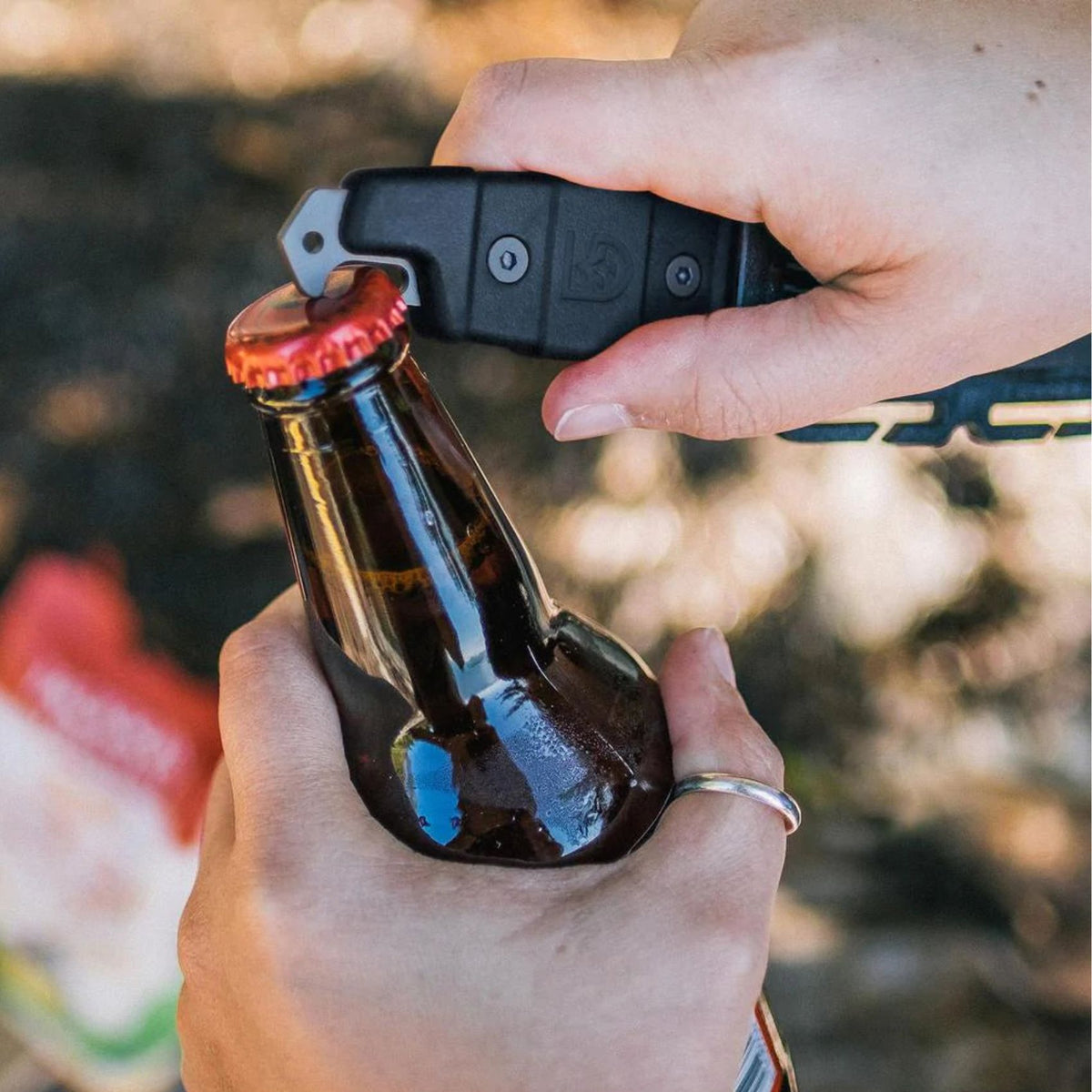 Hand model demonstrating bottle opening feature of Gear Aid Akua River Knife