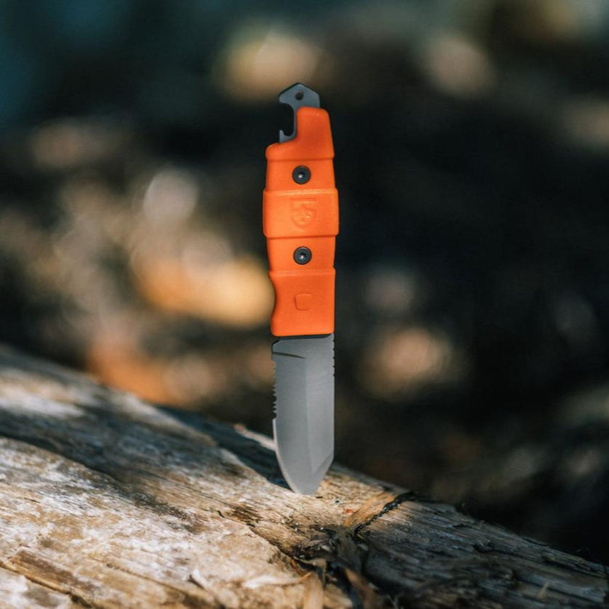 Gear Aid Buri Knife with Orange Handle resting in wood