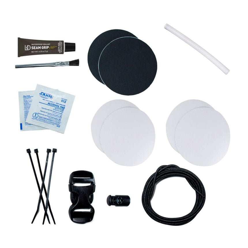 Gear Aid Tenacious Tape Camp Repair Kit Contents Laid out : 4 clear Tenacious Tape patches (7.6 cm rounds), 2 black nylon Tenacious Tape patches (7.6 cm rounds), Seam Grip WP sealant (7g), applicator brush, two alcohol wipes, one hot melt stick, four zip ties, 25mm Dual-Adjust Buckle, Ellipse Cord Lock, and 2m of Shock Cord