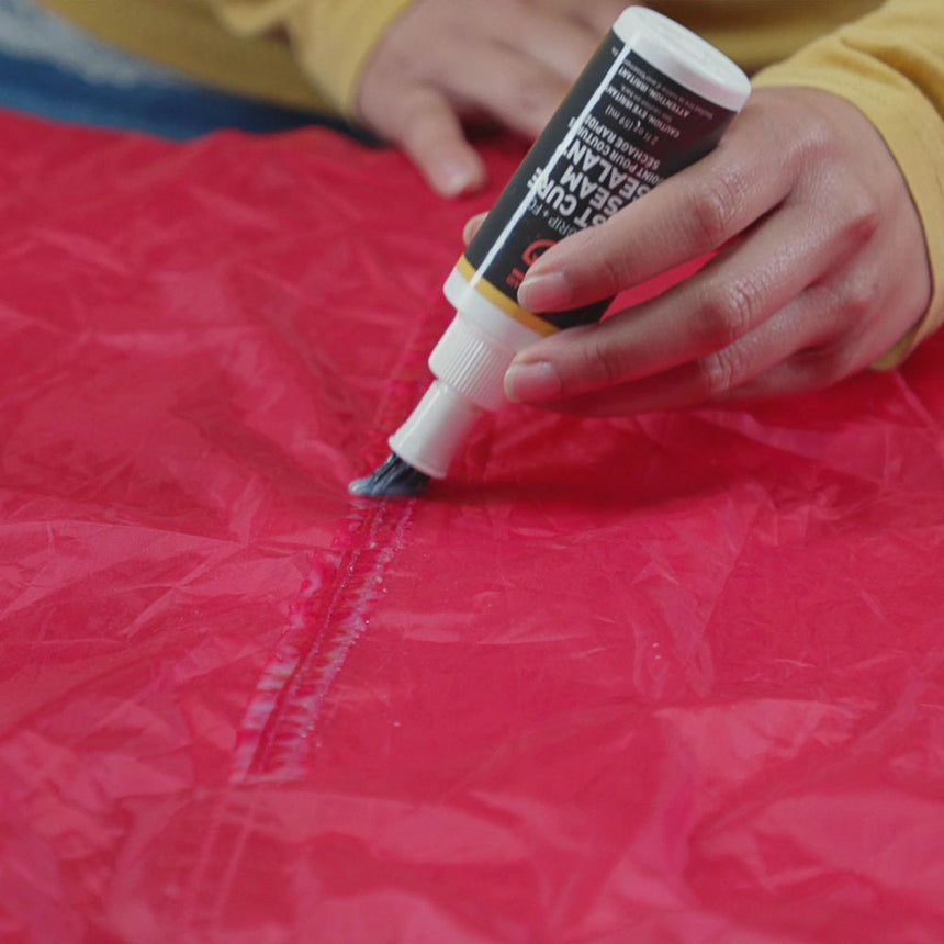 60ml Bottle of Gear Aid Seam Grip Fast Cure Tent Seam Sealant being applied to the seam of a red tent