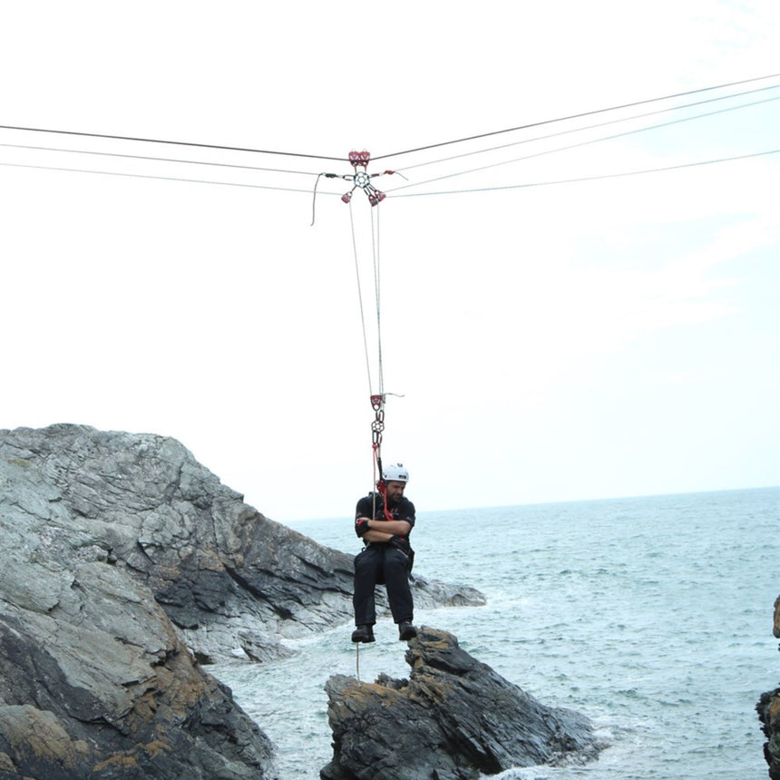 A high-angle rescue setup over coastal rocks using ISC HALO Rigging Plate and red pulleys, highlighting multi-line rigging.