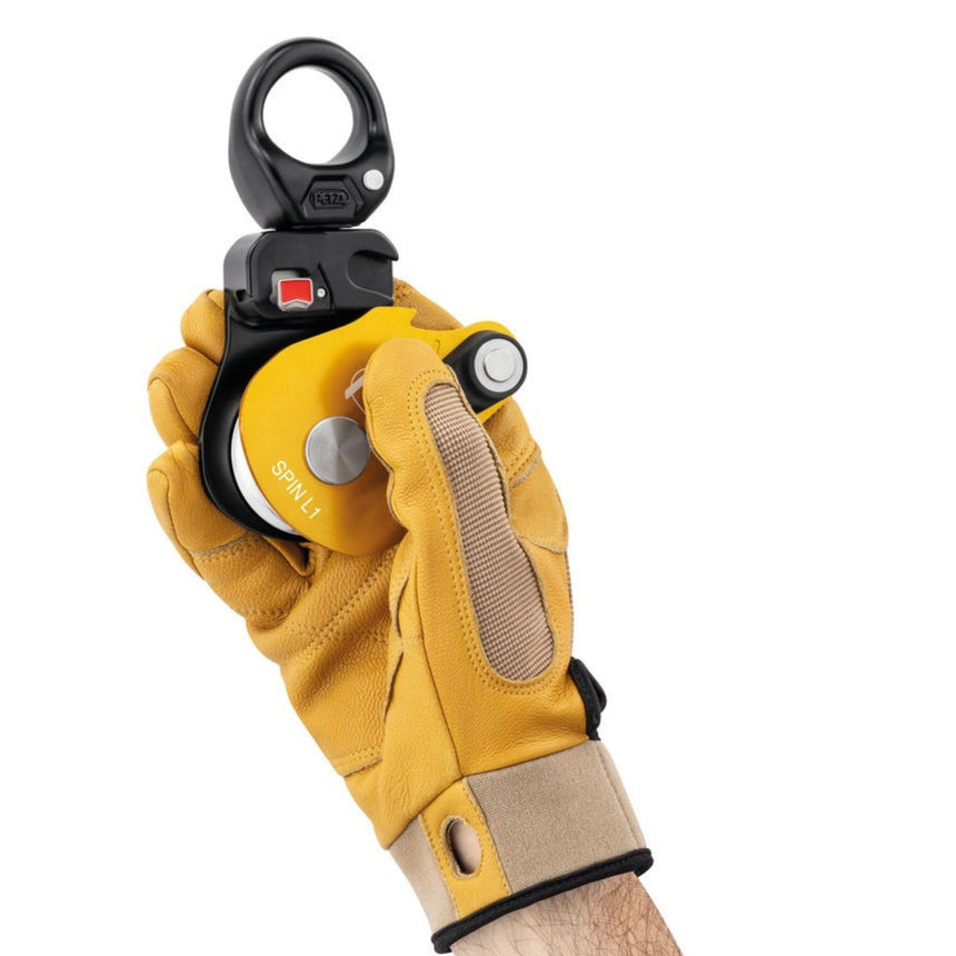 Professional wearing gloves holding Petzl Spin L1 Pulley showing Triple-action opening of the moving side plate is quick and easy, even with gloves on.