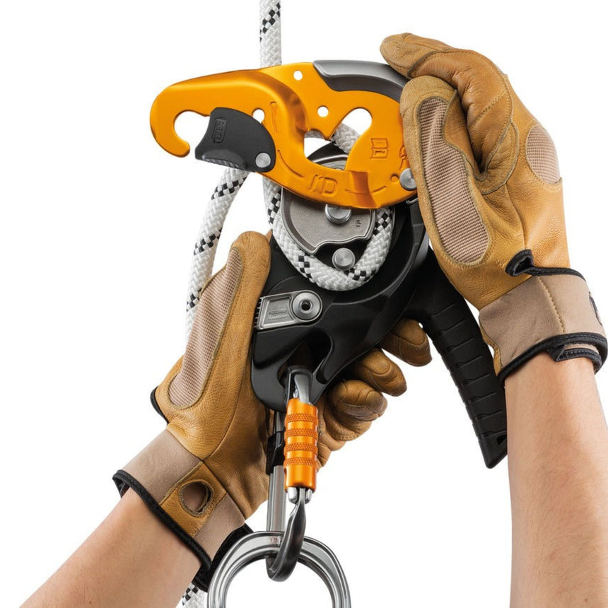 Professional wearing gloves demonstrating Petzl ID S descender safety gate on the moving side plate that allows the rope to be installed easily while the device
remains connected to the anchor.