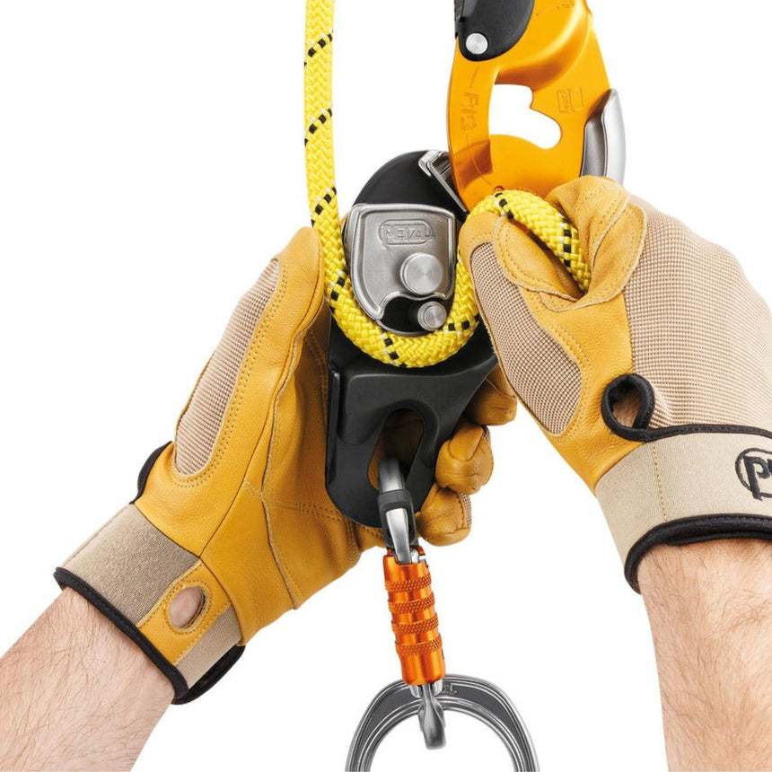 Professional wearing gloves installing a rope on the Petzl Rig descender. The safety gate on the moving side plate
allows the rope to be installed easily while the device remains connected to the harness.
