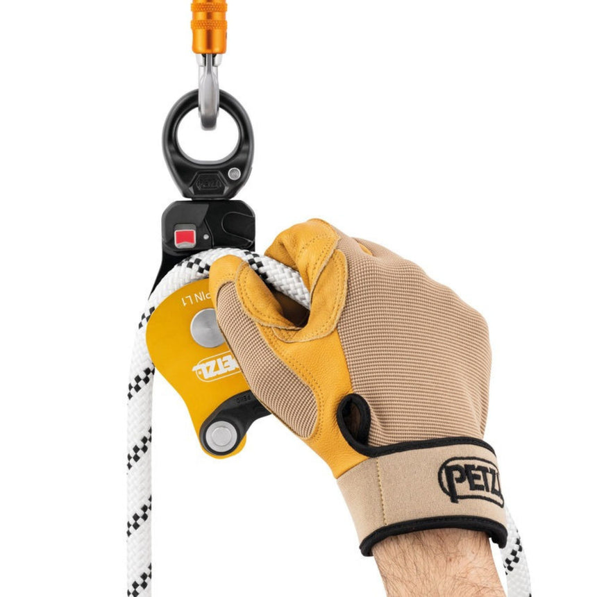 Professional wearing gloves installing a rope on the Petzl Spin L1 Pulley while it is connected to the anchor