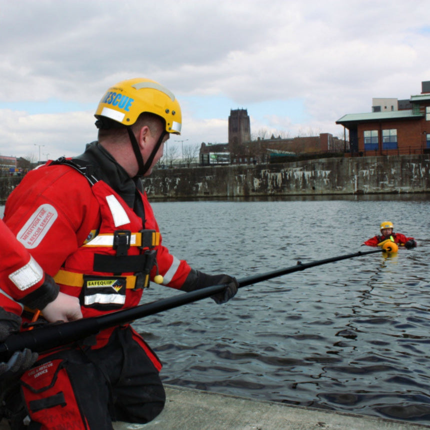 A rescue professional using a Reach and Rescue Pole to assist a person in water, demonstrating its long reach and effectiveness in water rescue operations.