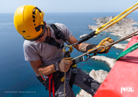 Technician wearing a helmet and harness while working on a telecommunications tower.