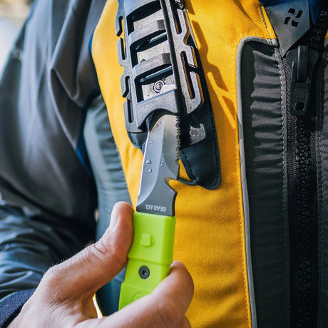 Hand model demonstrating Green Gear Aid Akua River Knife and black sheath storage holder attached to PFD 
