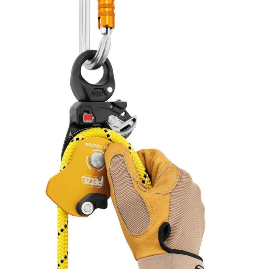 Professional wearing gloves installing a rope on the Petzl Pro Traxion pulley when the pulley is connected to the anchor.