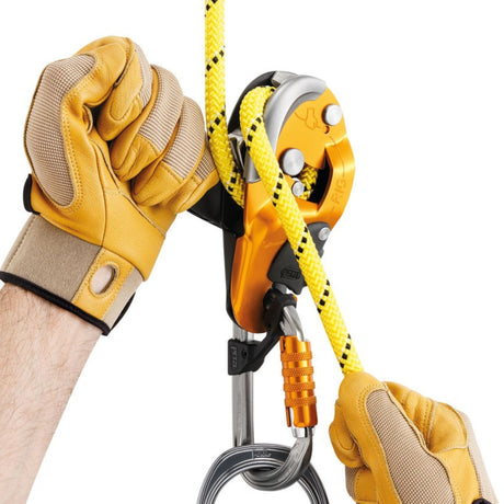 Professional wearing gloves operating the Petzl Rig descender ergonomic handle which allows unlocking the rope and comfortably controlling the descent.