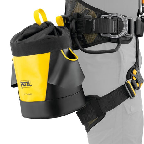 Professional demonstrating the Petzl Tool Bag 6 Tool Pouch insterfast quick connection accessory feature which makes it easy to install the Toolbag pouch on the harness, providing a compact solution and improved access to equipment.