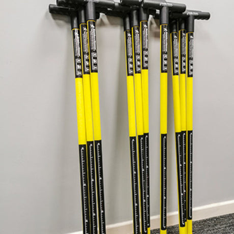 A set of Reach and Rescue search poles neatly stacked against a grey wall, showcasing the yellow fiberglass shafts and ergonomic black T-bar handles